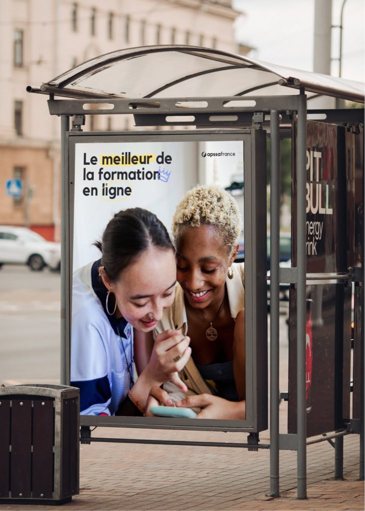 Affiche Apssa France dans un abribus, accroche Le meilleur de la formation en ligne au-dessus de deux jeunes femmes souriantes