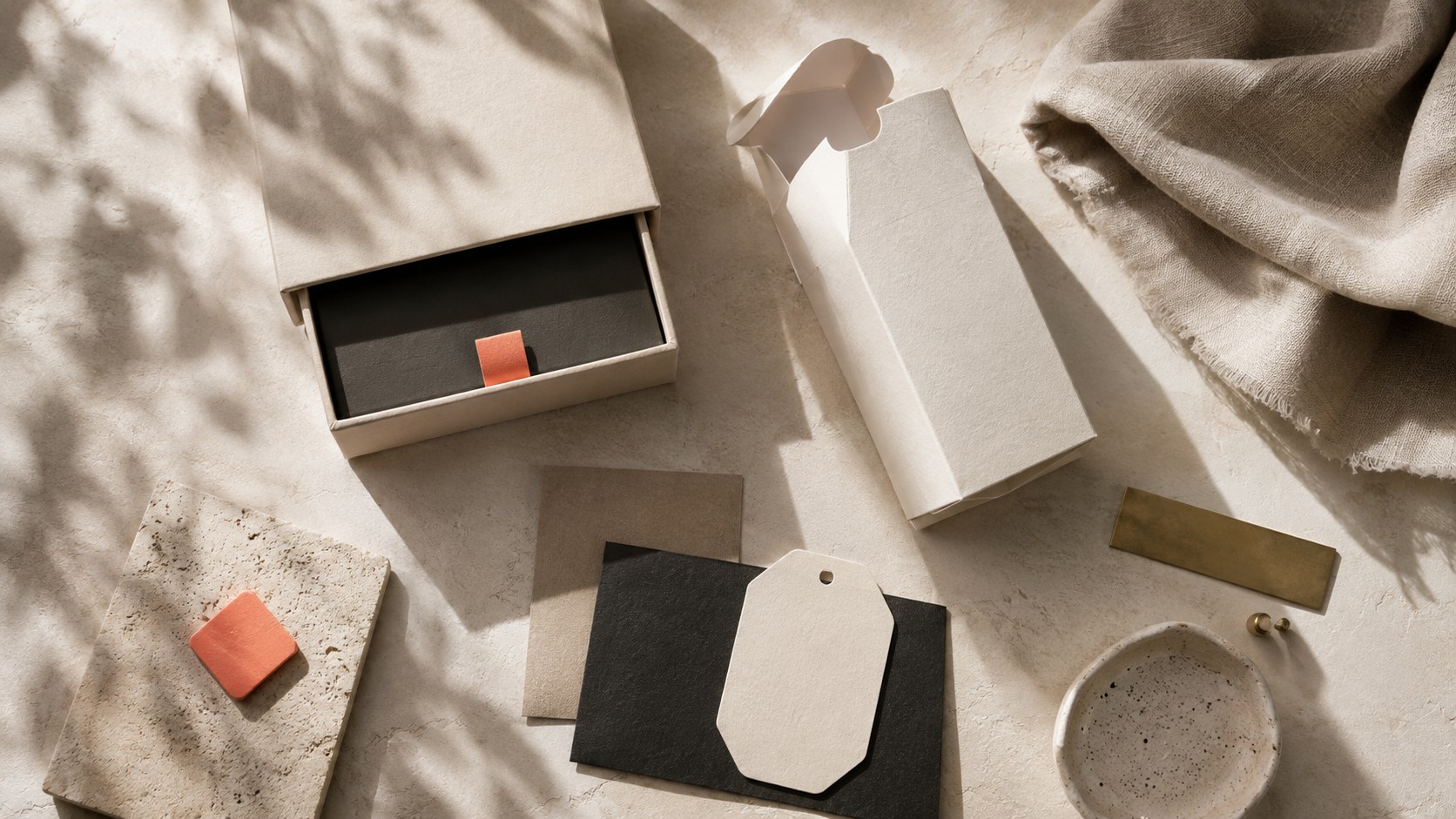 Photographie produit premium en flat lay, packaging crème et noir avec accents corail et laiton, lumière homogène