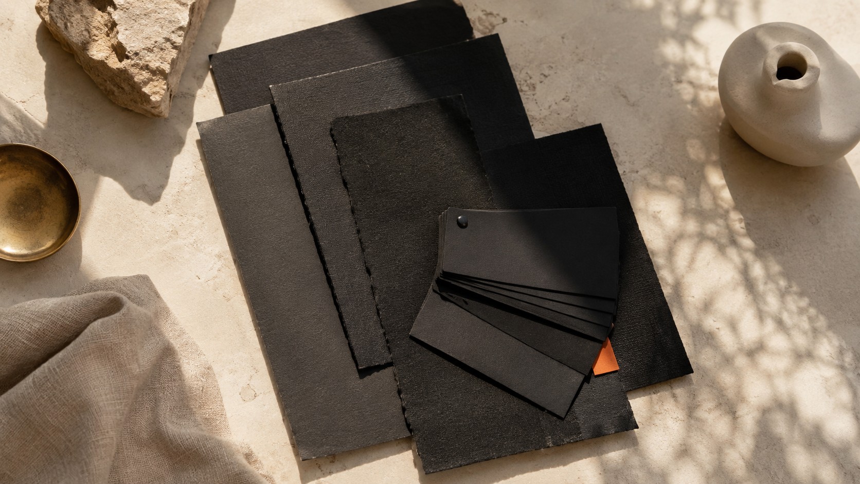 Nuancier de branding en couleur noire, papiers noirs, pierre, céramique, laiton et lin avec accent corail